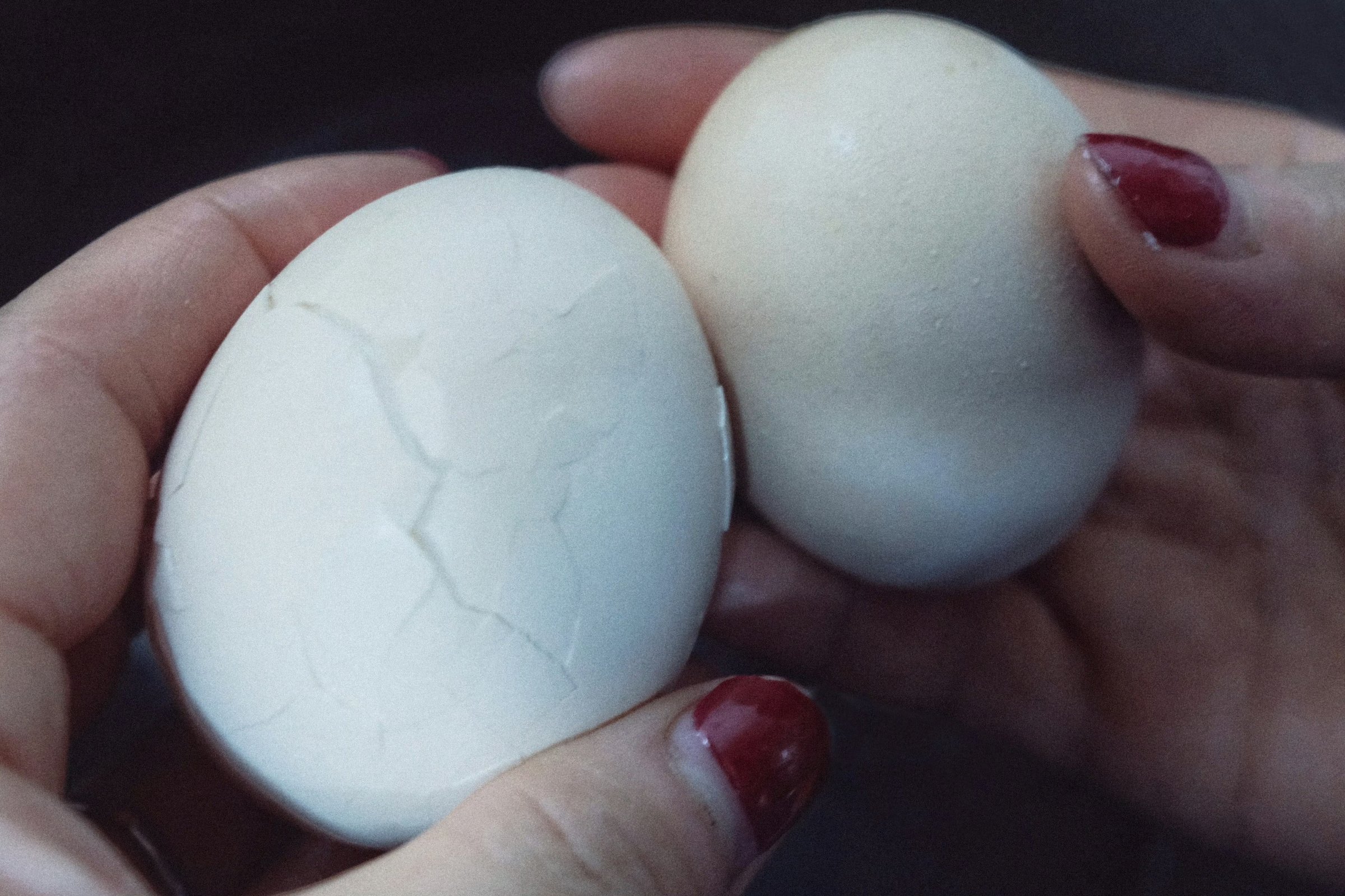 Two eggs held in a hand, one shell cracked all over